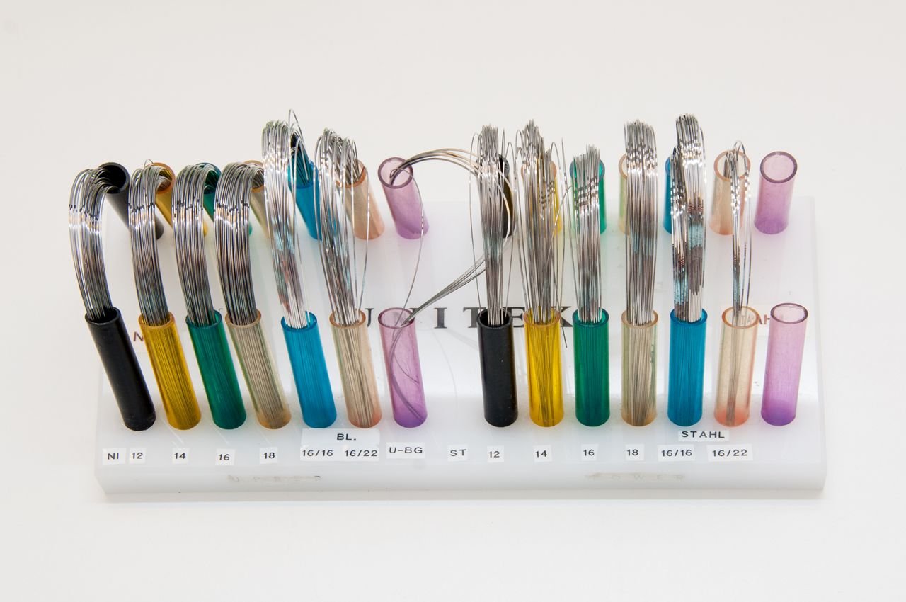 Display of colorful orthodontic wires arranged neatly on a stand.
