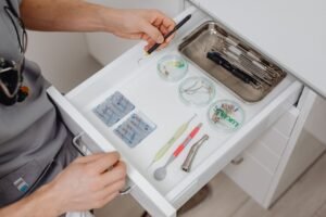 A dentist arranges dental tools in a clinic drawer, showing modern equipment.